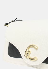 Borsa a mano in pelle bianca e nera con finitura testurizzata, chiusura a pattina e un accento in oro a forma di cerchio.