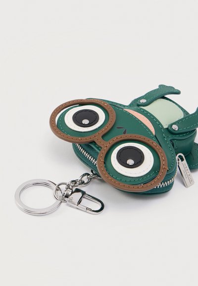 Πράσινο πορτοφόλι σε σχήμα βατράχου, κατασκευασμένο από λείο δέρμα με μεγάλα στρογγυλά μάτια, φερμουάρ και μεταλλικό κρίκο για κλειδιά.