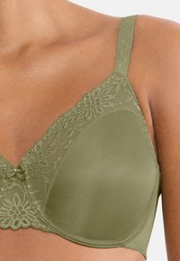 Oliwkowo zielony biustonosz z koronkową lamówką, gładkimi, satynowymi miseczkami oraz małą ozdobną kokardką na środku. Regulowane ramiączka zapewniają pewne dopasowanie.