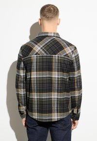 Camicia a quadri nera con motivi gialli, grigi e arancioni, dotata di colletto standard e maniche lunghe.