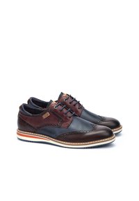 Chaussures en cuir marron et marine avec des détails brogue, des coutures contrastées et une semelle blanche comportant une rayure rouge et marine.