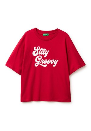 T-shirt oversize rossa in cotone con maniche corte e scollatura rotonda, caratterizzata da testo bianco che recita "Stay Groovy" in un font bold.