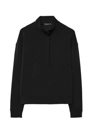 Musta collegetyyppinen pusero, jossa on korkea kaulus, puolivälissä oleva vetoketju edessä ja pitkät hihat. Valmistettu pehmeästä, sileäpintaisesta kankaasta.