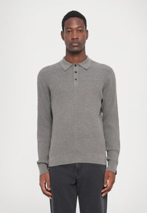 Polo din tricot gri, cu mânecă lungă, cu textură ribbed, închidere cu cinci butoane și guler plat, asortat cu blugi închiși la culoare.