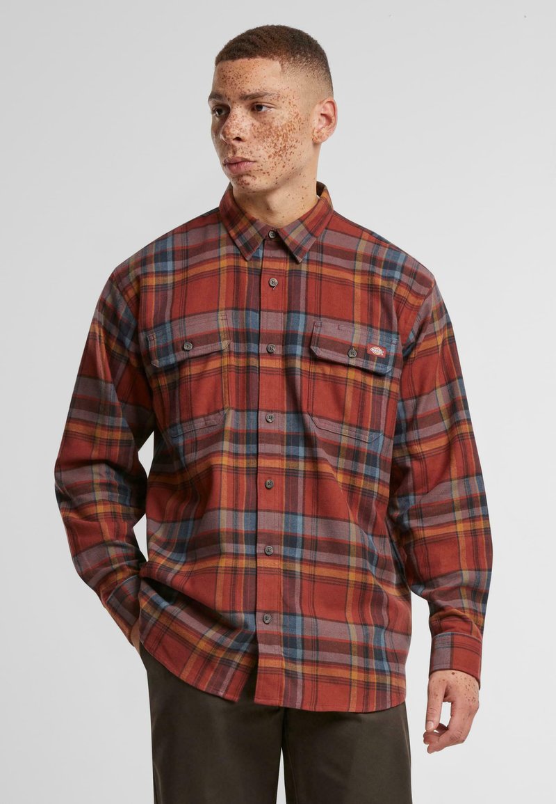 Plaid flannel shirt in red and gray tones, featuring long sleeves, button-down collar, two chest pockets, and a relaxed fit.