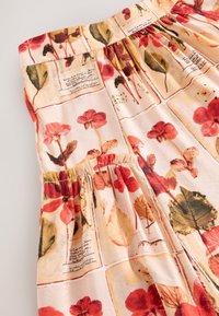 Kleid mit floralem Muster, das rote und grüne Blätter auf cremefarbenem Hintergrund zeigt. Elastischer Taillenbund mit sichtbarer Textur und Stoffdetails.