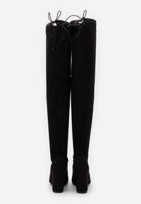 Botas negras sobre la rodilla hechas de suave ante, con una textura lisa, punta redondeada, tacones cuadrados altos y lazos ajustables en la parte superior.