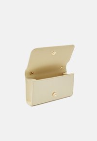 Beige läderclutch med en slät textur, utrustad med en tryckknappsstängning och gulddetaljer. Öppen design ger enkel åtkomst till det inre utrymmet.