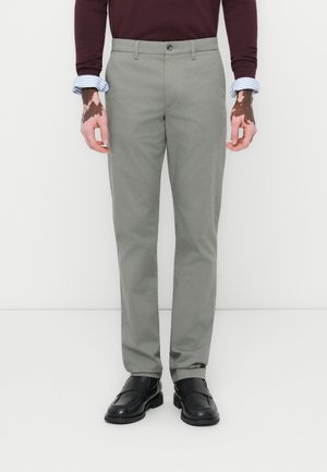 Light gray trousers with a slim fit, featuring a button closure and front pockets, paired with black shoes and a dark long-sleeve top.