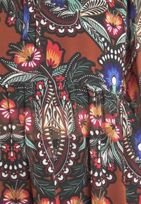 Květinová potištěná látka s barevnými květy v červené, oranžové, modré a zelené barvě na hnědém pozadí; obsahuje skládání.