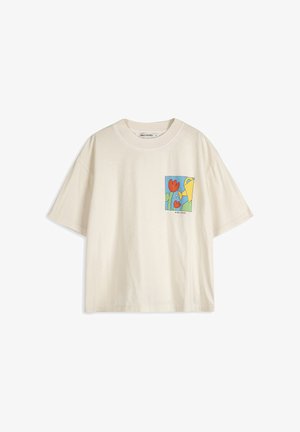 T-shirt crème à manches courtes avec un petit motif coloré de fleurs rouges et un arrosoir jaune sur la zone de la poche gauche de la poitrine.
