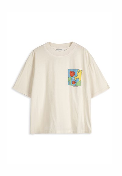 T-shirt crème à manches courtes avec un petit motif coloré de fleurs rouges et un arrosoir jaune sur la zone de la poche gauche de la poitrine.