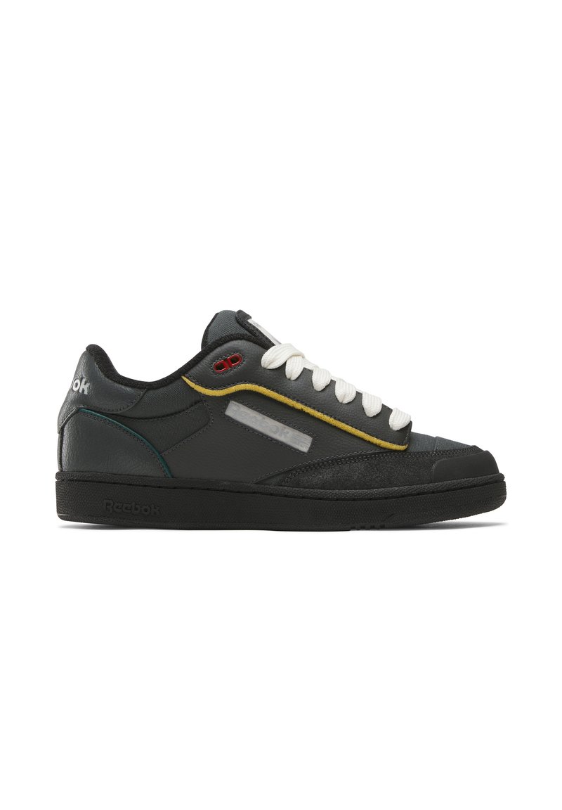 Black leather sneakers with white laces, yellow and teal accents, and a textured black sole. Features a reflective side panel and brand logo.