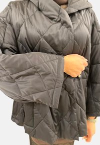 Veste noire matelassée avec capuche, dotée de manches larges et d'un motif en losanges. Fabriquée en matériau lisse et léger pour la chaleur et le confort.