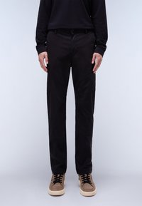 Black cargo pants with a straight cut, made of smooth fabric. Features side pockets, a button closure, and worn with beige sneakers.