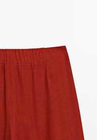 Red, elastic waistband pants with a smooth, lightweight texture. The fabric appears breathable, suitable for casual wear.