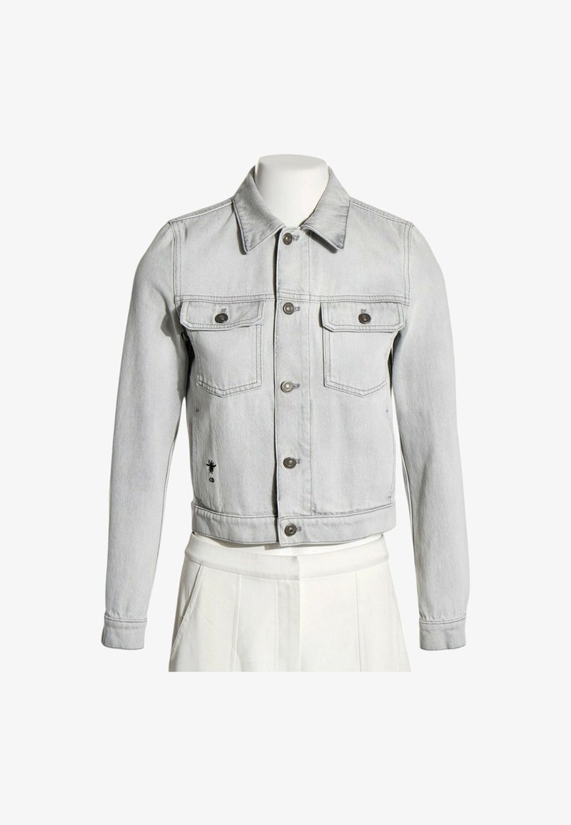 Veste en jean gris clair avec boutons sur le devant, deux poches poitrine à rabat et manches longues, présentée sur un torse de mannequin blanc.
