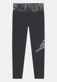 Leggings neri con una cintura ampia e decorata. Presentano un grande logo Jumpman riflettente sulla parte inferiore della gamba. Realizzati in materiale elastico.