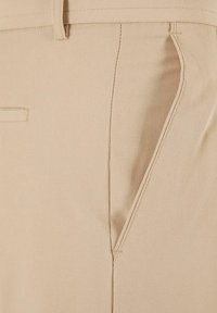 Beige textielbroeken met een gladde afwerking, voorzien van een zijzak en een gestikt tailleband. De stof lijkt lichtgewicht en duurzaam.