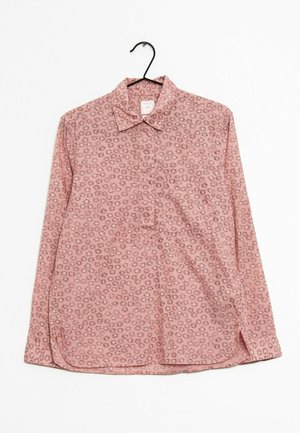 Pinkes Langarmhemd mit Knöpfen und kleinem dunklem Blumenmuster, das auf einem schwarzen Kleiderbügel vor weißem Hintergrund hängt.