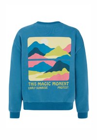 Felpa blu con stampa sul retro che presenta un paesaggio montano stilizzato nei colori giallo, rosa e verde, con testo sottostante.