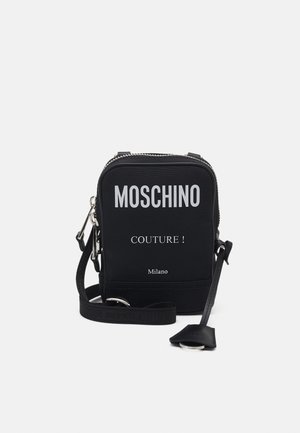 Czarna kompaktowa torba na ramię Moschino z białym napisem "MOSCHINO COUTURE! Milano" i regulowanym paskiem na białym tle.