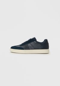 Navy blue sneakers featuring a mix of smooth and textured materials, with a white sole, flat laces, and subtle side panel detailing.
