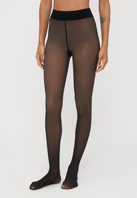 Meias opacas pretas com uma textura suave, cintura alta e design sem costura, cobrindo completamente as pernas e os pés.
