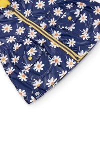 Veste bleu marine avec des fleurs de marguerite blanches, fermeture éclair jaune, deux poches avant à rabat avec boutons jaunes et doublure intérieure jaune.