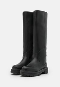 Černé kozačky do půli lýtek vyrobené z hladké kůže, s kulatou špičkou a silnou gumovou podešví. Obsahují minimální prošívání a elegantní design.