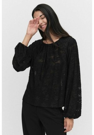 Blouse noire à manches bouffantes, en tissu transparent avec broderie florale. Coupe décontractée et encolure ronde, associée à un pantalon noir.