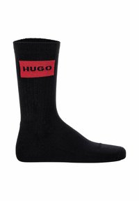 Schwarze Baumwollsocken mit gerippter Textur, die ein rotes rechteckiges Logo aufweisen, auf dem in fetten schwarzen Buchstaben "HUGO" steht.