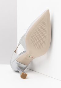 Scarpa con tacco alto argento dal design elegante, tomaia in tessuto testurizzato, punta affusolata e suola beige minimalista. Presenta un tacco a forma quadrata.