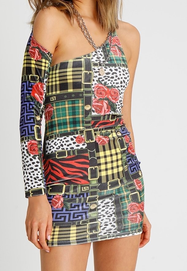 Femme portant une mini-robe asymétrique avec des motifs patchwork à carreaux, imprimé animal, roses rouges et ceintures noires.