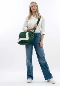 Grøn syntetisk crossbody-taske med en hvid diagonal detalje, firkantet form og justerbar rem. Robust tekstur, kompakt design.