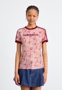 Ziedu raksta, īso piedurkņu Adidas t-krekls ar bordo ribām ap kaklu un piedurknēm, ar izteiktu bordo logotipu uz krūtīm.