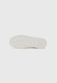 White rubber shoe sole with a textured pattern, featuring a logo and curved design elements for traction and support.