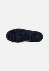 Rubber shoe sole featuring circular and wave patterns, primarily dark navy color with speckles, smooth texture, and defined tread design.