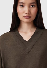 Maglione a V in maglia di colore verde oliva scuro, con una superficie liscia e sottili dettagli di cucitura sul colletto e sulle maniche.