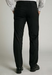 Pantalones de vestir negros con corte recto, textura suave y dos bolsillos traseros. Cuenta con trabillas para cinturón y un ajuste entallado. Llevado con zapatos negros.