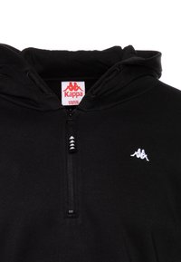 Sudadera negra con media cremallera, que presenta un logo bordado en blanco en el lado izquierdo del pecho y una etiqueta Kappa en el interior. Textura de tela suave.