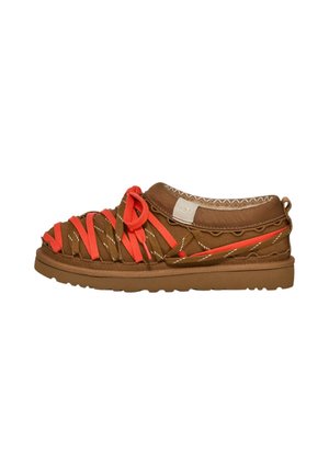 Scarpa slip-on marrone con lacci intrecciati arancione brillante e suola spessa, con un'asola di tessuto sul tallone.