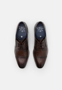Chaussures habillées en cuir marron avec une finition lisse, présentant un design à lacets et des détails de couture subtils. L'intérieur est doublé de bleu.