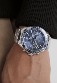 Orologio in acciaio inossidabile silver con quadrante blu, indicatori luminosi e tre sottodial; presenta un lunetta blu girevole e display della data.