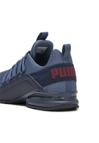 Zapatillas deportivas para hombre con una parte superior de malla transpirable en color azul marino, detalles en azul oscuro y un prominente logo rojo de "PUMA" en el talón. Presenta una suela estilizada y curva.