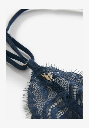 Laivastonsininen pitsirintaliivit, joissa on herkät kukkakuviot, säädettävät olkaimet ja kultainen metallinen solki sulkemiseen. Pitsissä on tekstuuri ja aaltoilevat reunat.