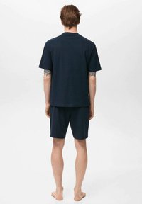 Dunkelblaues Baumwoll-Pyjama-Set mit einem kurzärmeligen Shirt und Shorts, mit lockerer Passform und glatter Textur. Keine sichtbaren Muster oder Akzente.