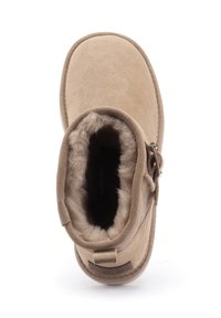 Tan suède enkellaars met een zachte, fluffy voering. Bevat een zijrits en een lus aan de achterkant voor gemakkelijk aan- en uittrekken.
