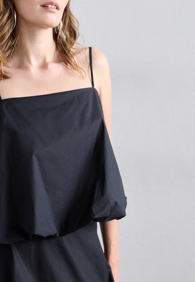 Haut sans manches noir avec un décolleté carré et un tissu fluide. Équipé de fines bretelles et d'un ourlet froncé pour une silhouette décontractée.