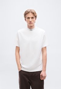 Λευκό κοντομάνικο t-shirt με ψηλό γιακά και μαύρο λογότυπο "BOSS" στο λαιμό, με ομαλή υφή και άνετη εφαρμογή.